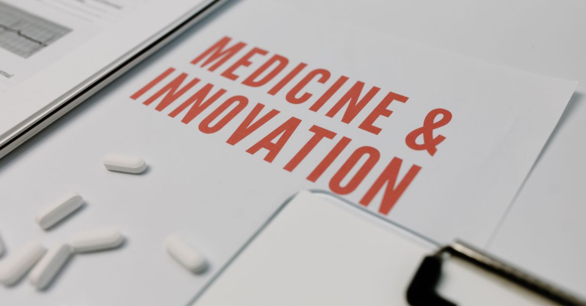 Close-up of 'Medicine & Innovation' paper with pills and documents on a desk.